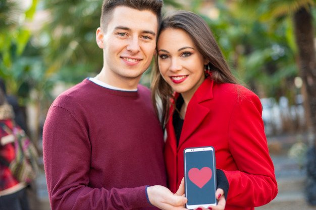 couple-kissing-while-showing-smartphone-with-heart-shape-it-dating-application-concept_53419-8979