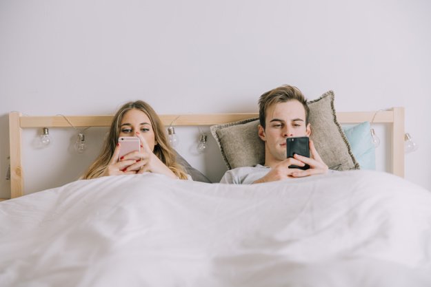 couple-using-smartphones-bed_23-2147739725