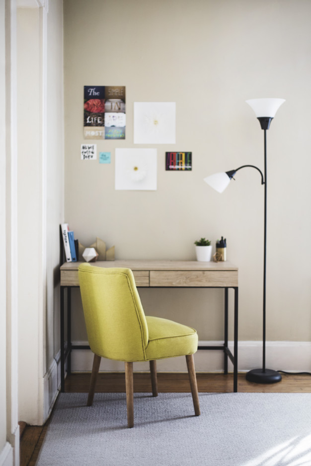 vertical-shot-yellow-chair-tall-lamp-near-wooden-table-with-books-plant-pots-it_181624-1826